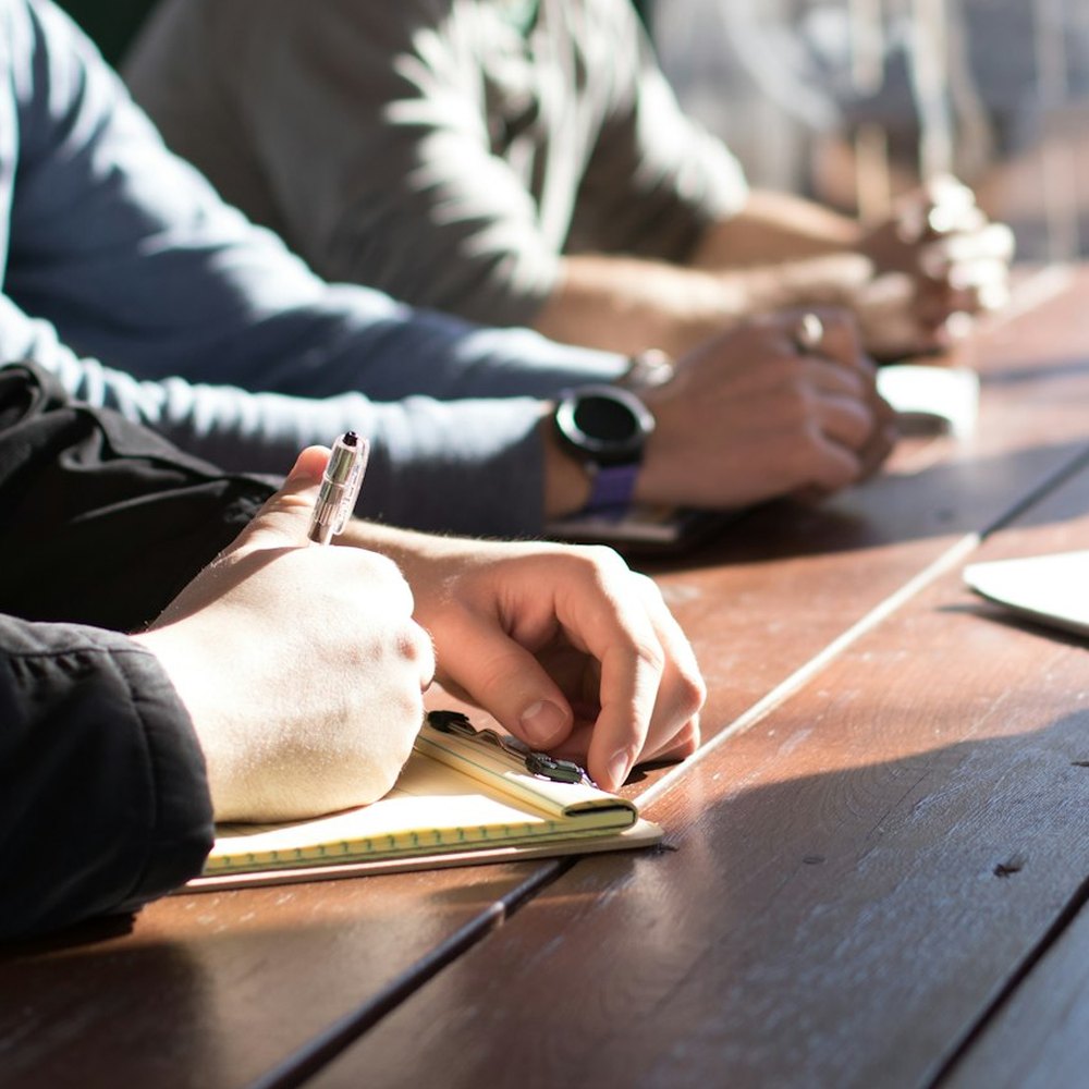 Riunione di lavoro attorno a un tavolo, con appunti e mani in primo piano